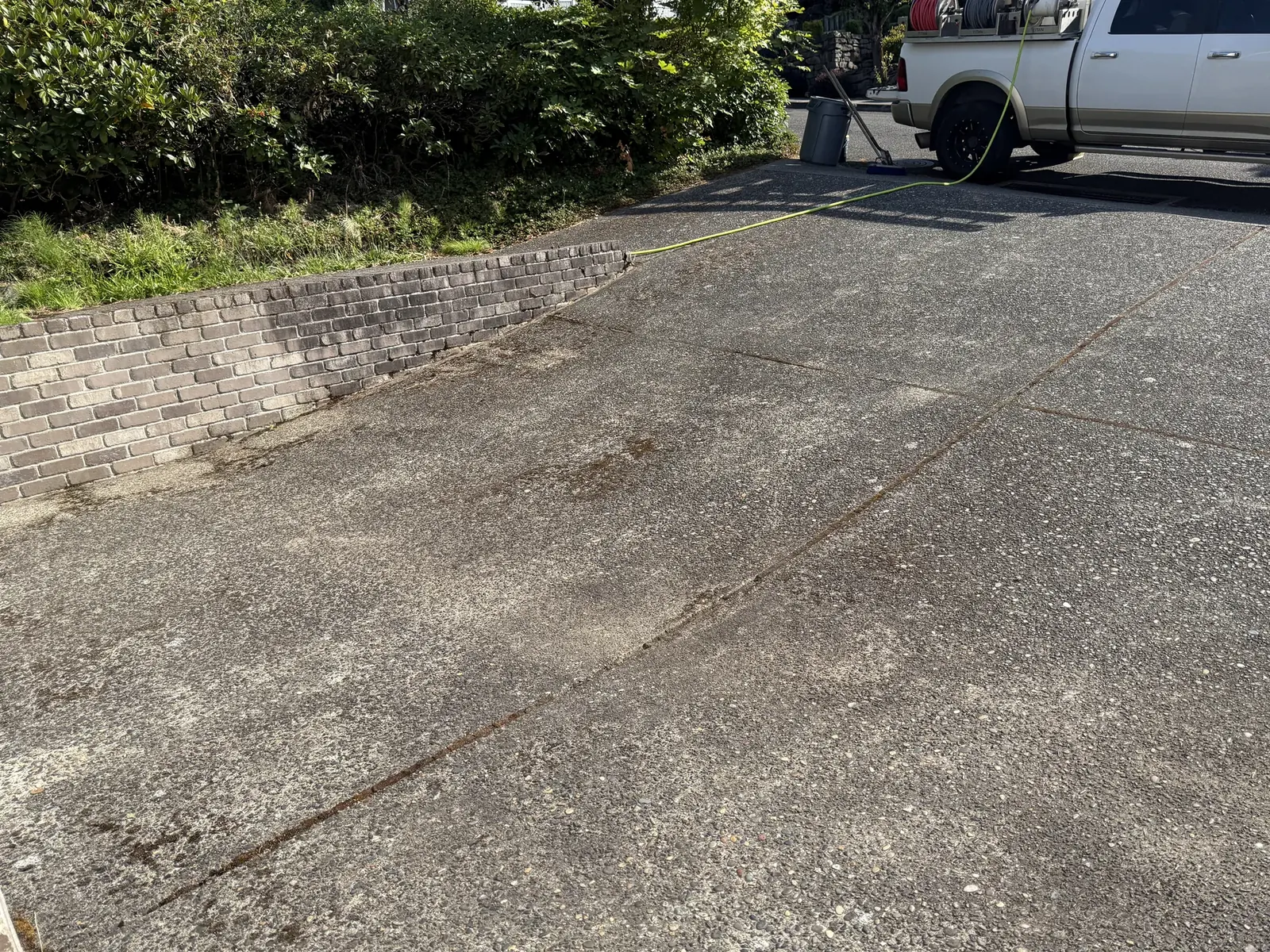 Exposed-aggregate driveway before cleaning with moss near the brick wall