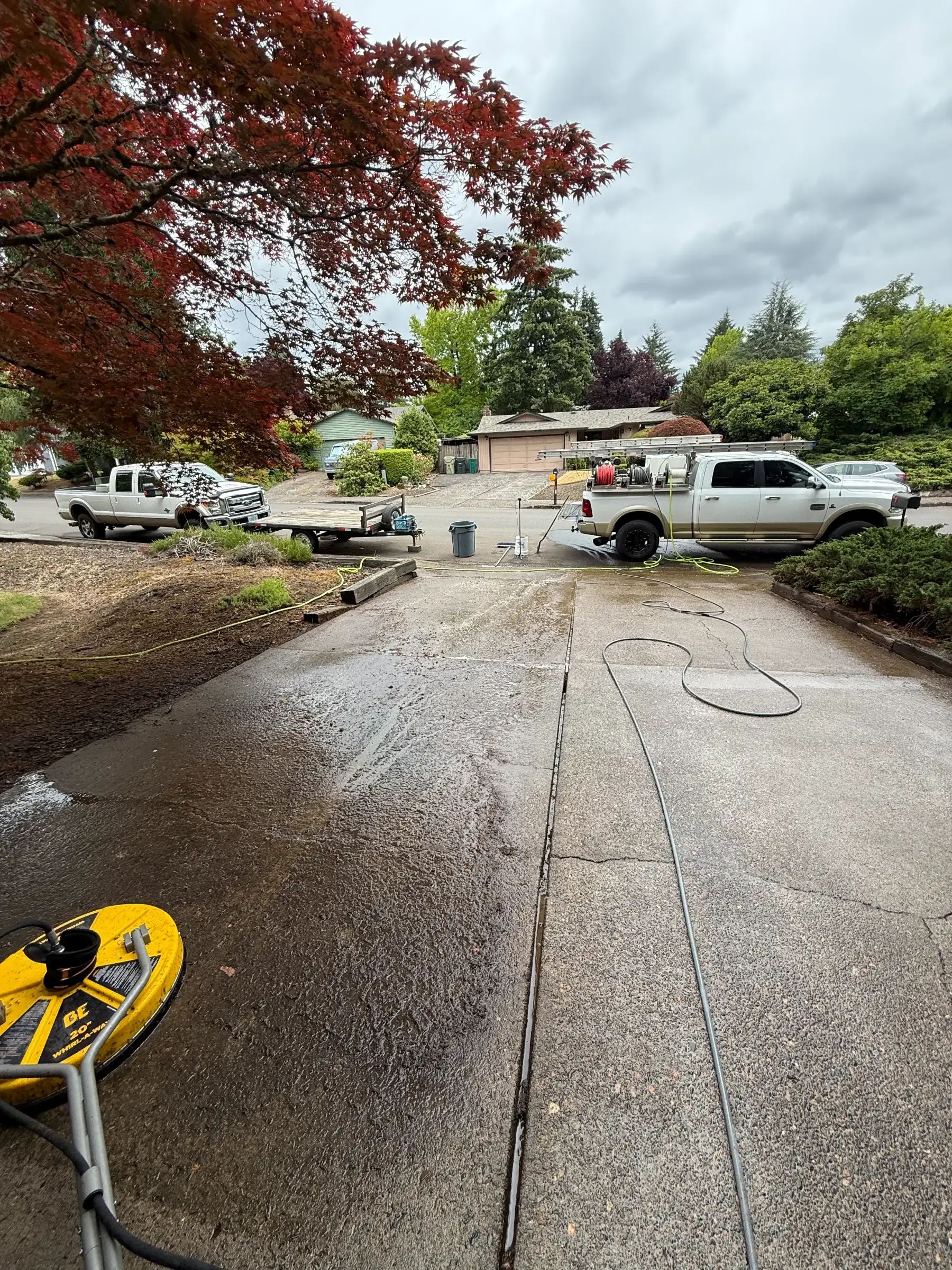 Wide in-progress driveway cleaning photo with surface cleaner and wet concrete near Beaverton Oregon