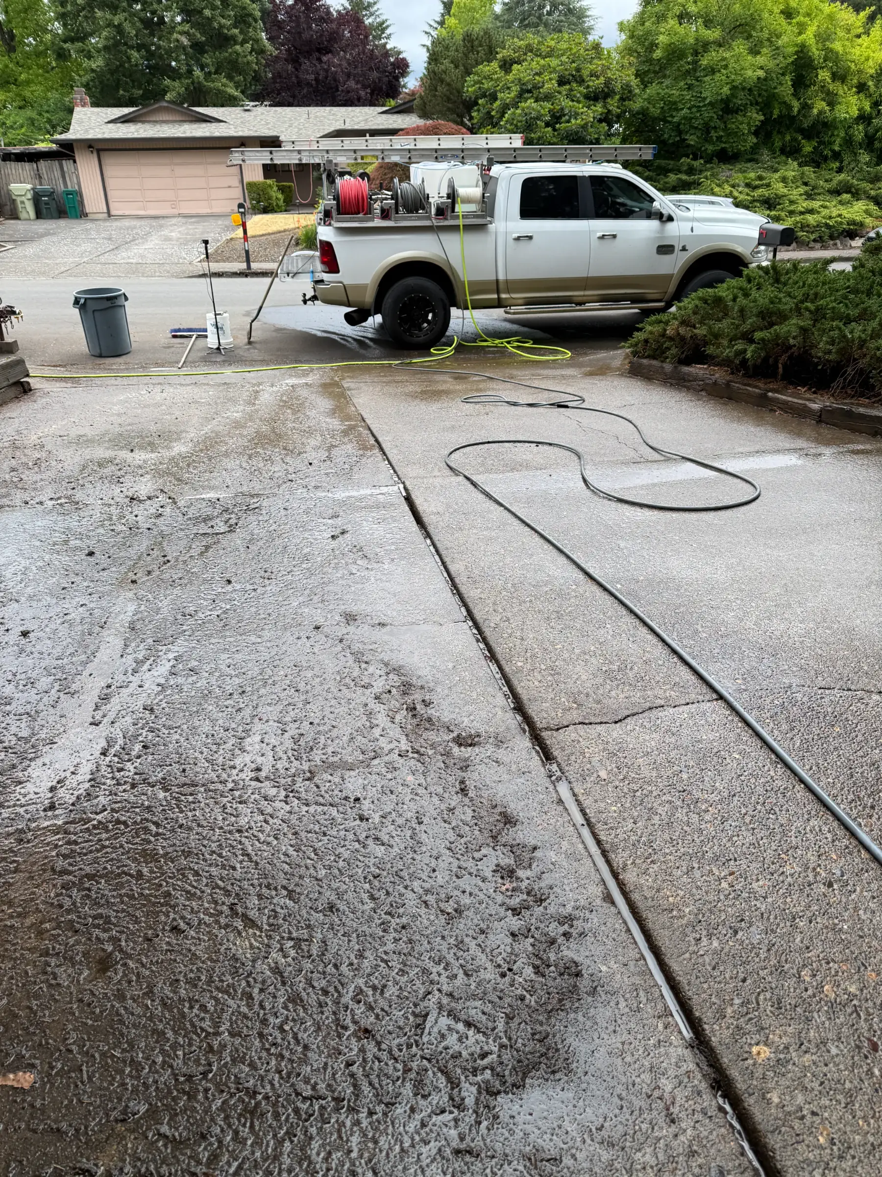 Suds Doctor pressure washing truck and hoses during driveway cleaning near Aloha Oregon