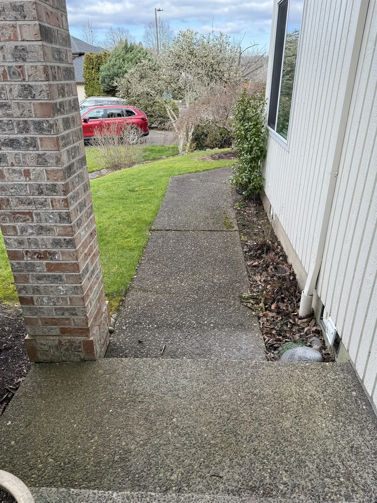 Exposed aggregate walkway beside a Beaverton home before cleaning with shaded organic buildup