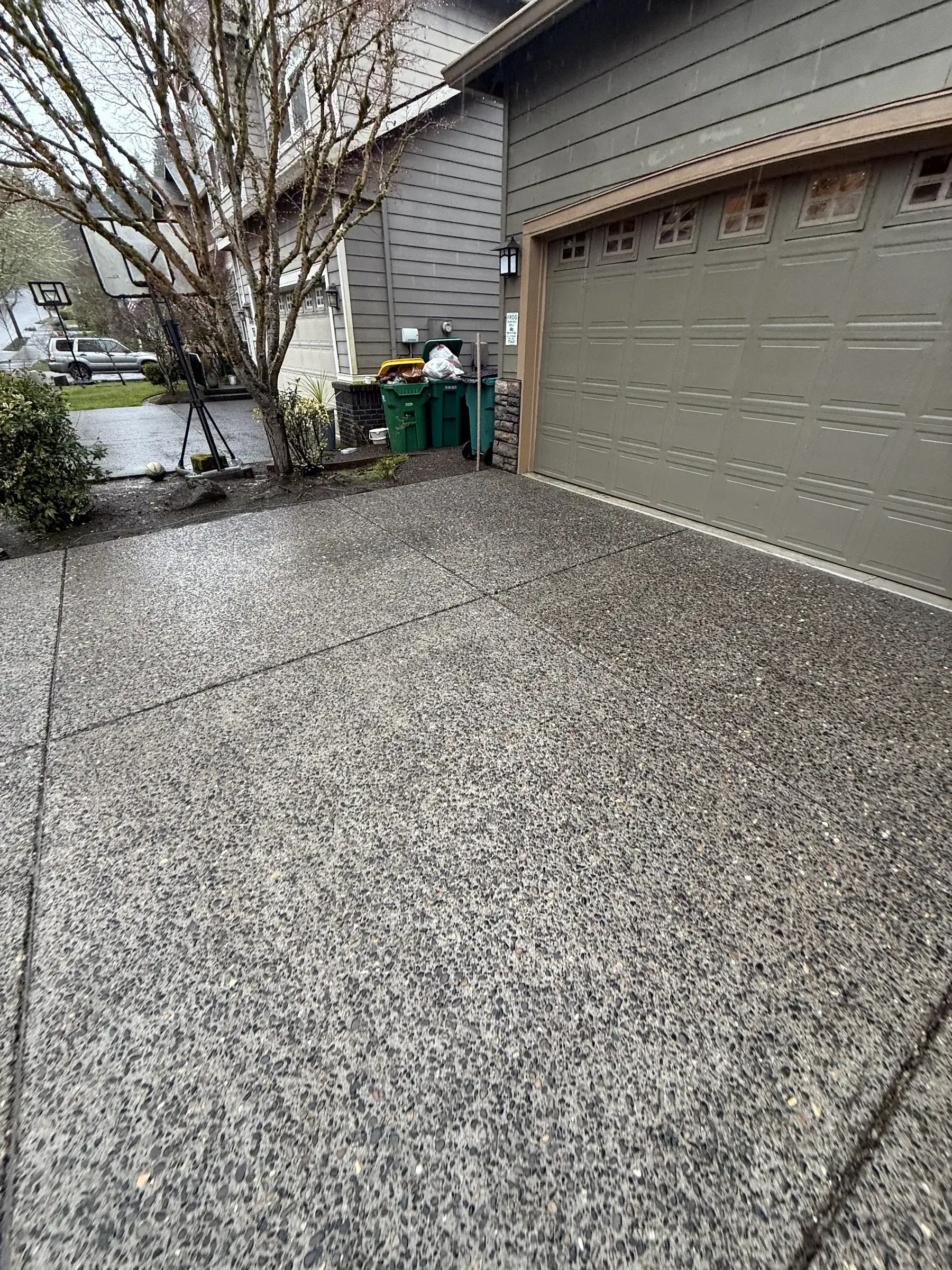 Cleaned exposed aggregate driveway near garage after rainy-day pressure washing in South Beaverton