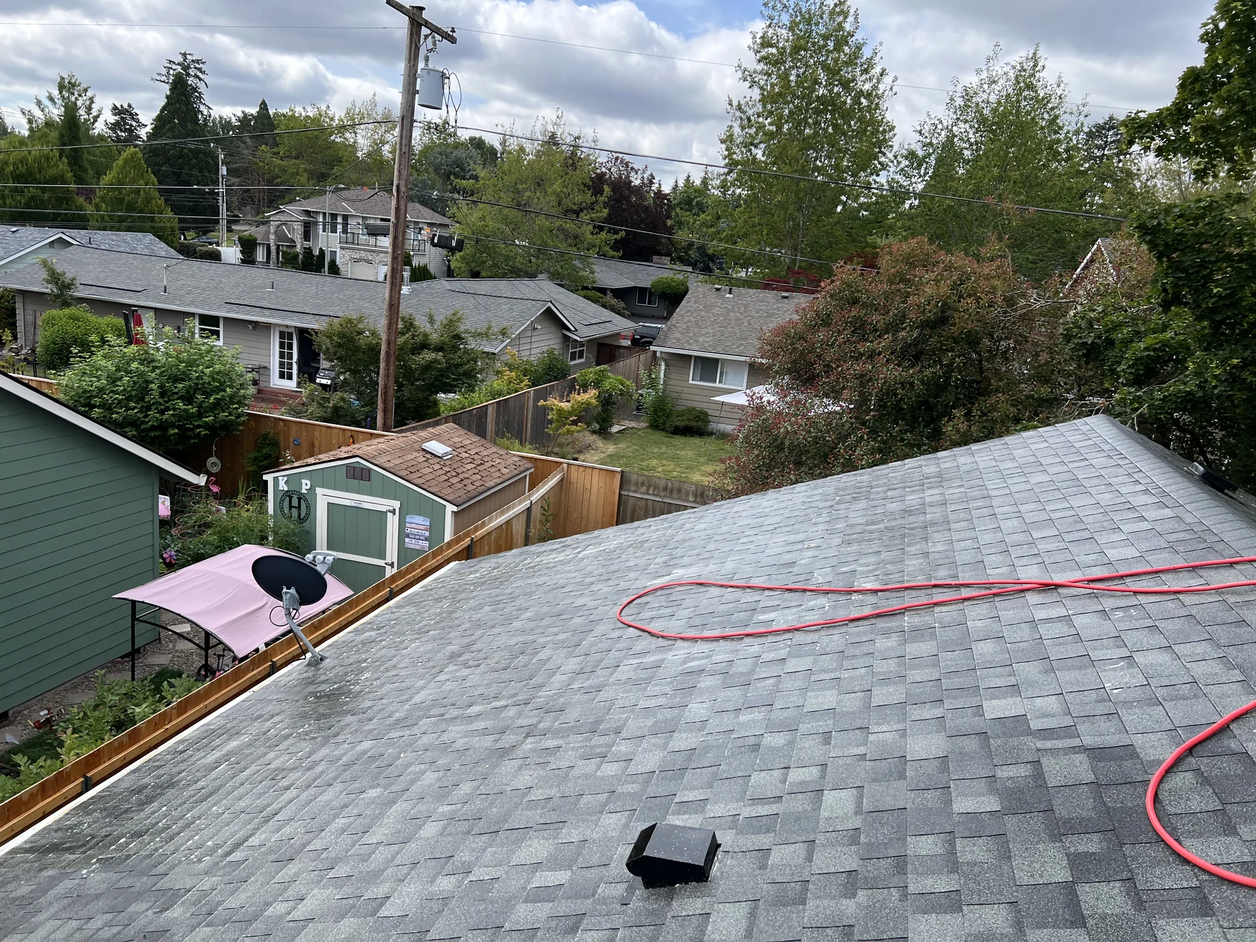 Roof treatment hose and treated shingle plane during a Beaverton roof moss treatment project