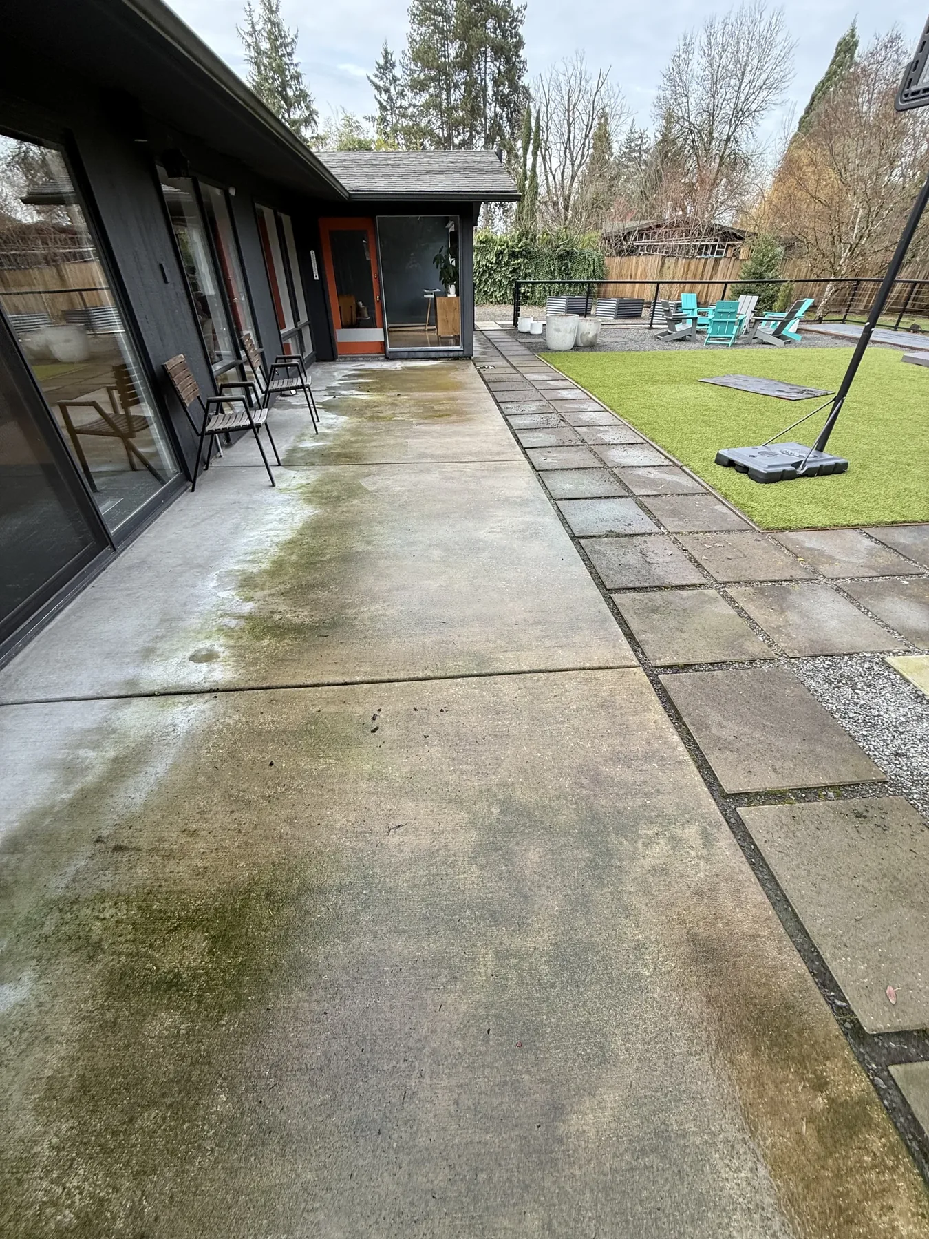 Back patio concrete beside a Cedar Mill home with darker organic buildup before cleaning