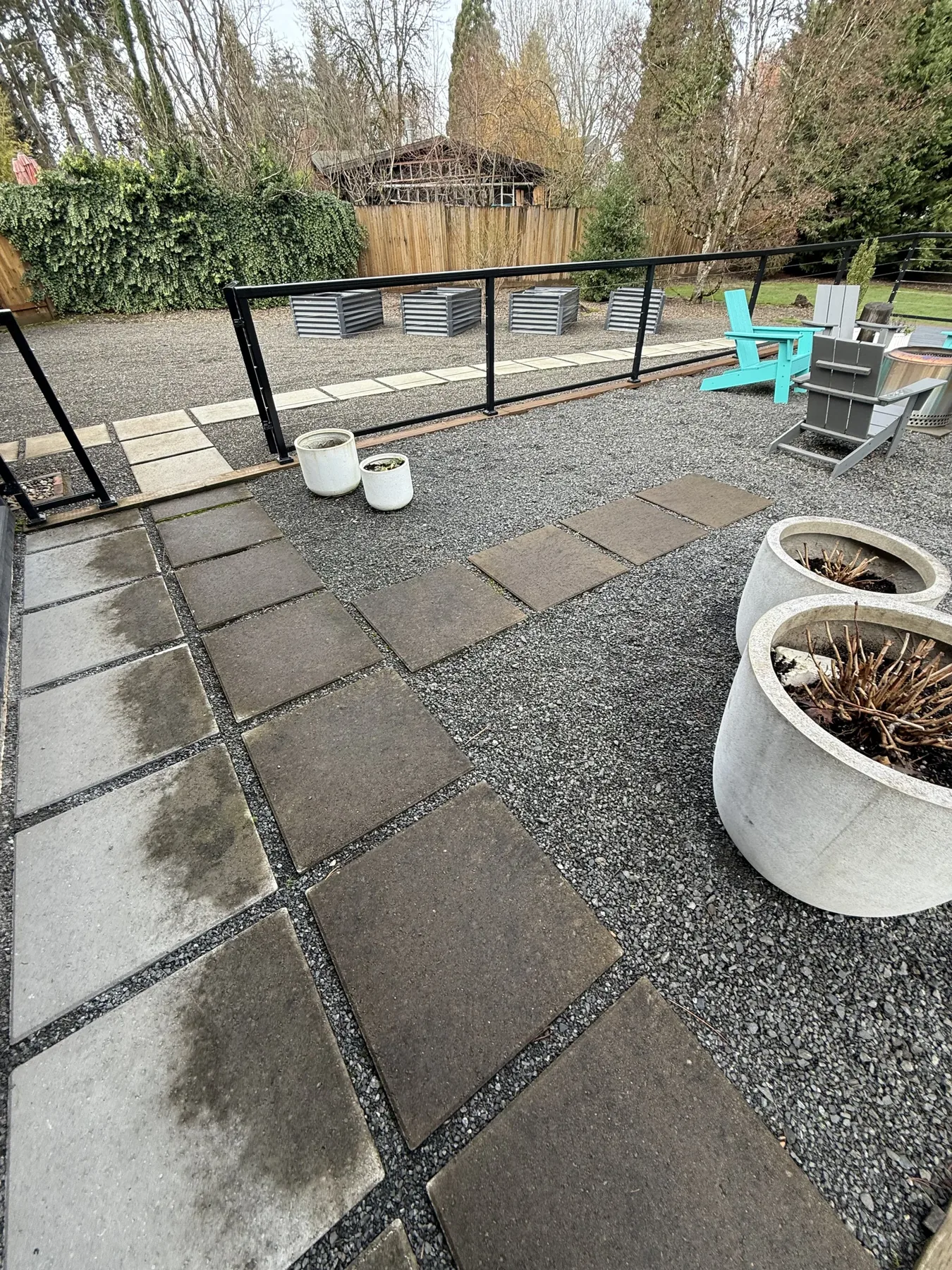 Cedar Mill patio slabs near planters, gravel, and backyard railing