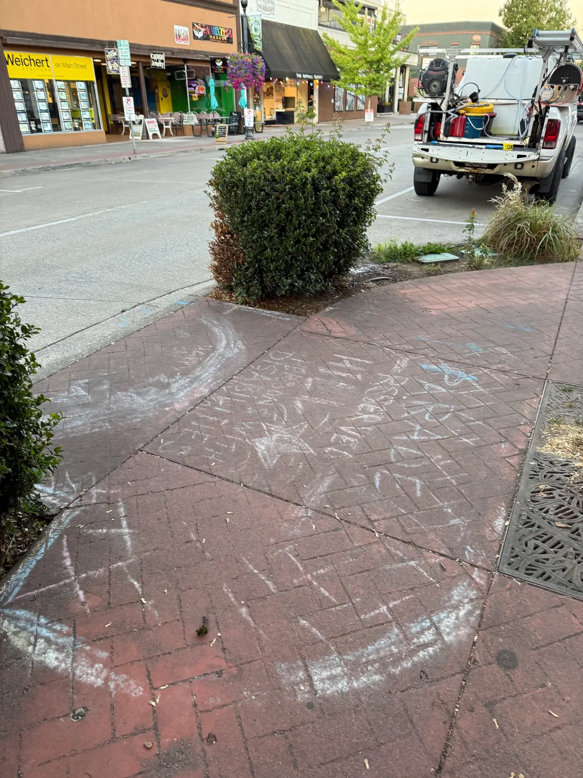 Wide view of chalk-covered stamped sidewalk on E Main Street before cleaning