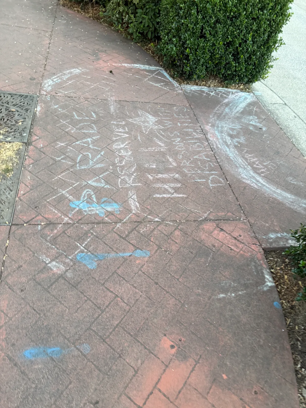 White and blue parade chalk covering stamped red sidewalk panels in Downtown Hillsboro before cleaning