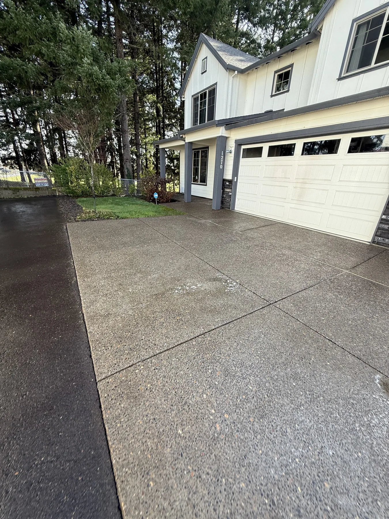Finished Forest Grove concrete driveway after pressure washing near a garage and tree line