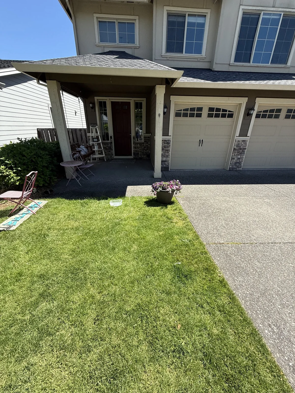 Watering lawn and nearby plants before pressure washing a Forest Grove driveway