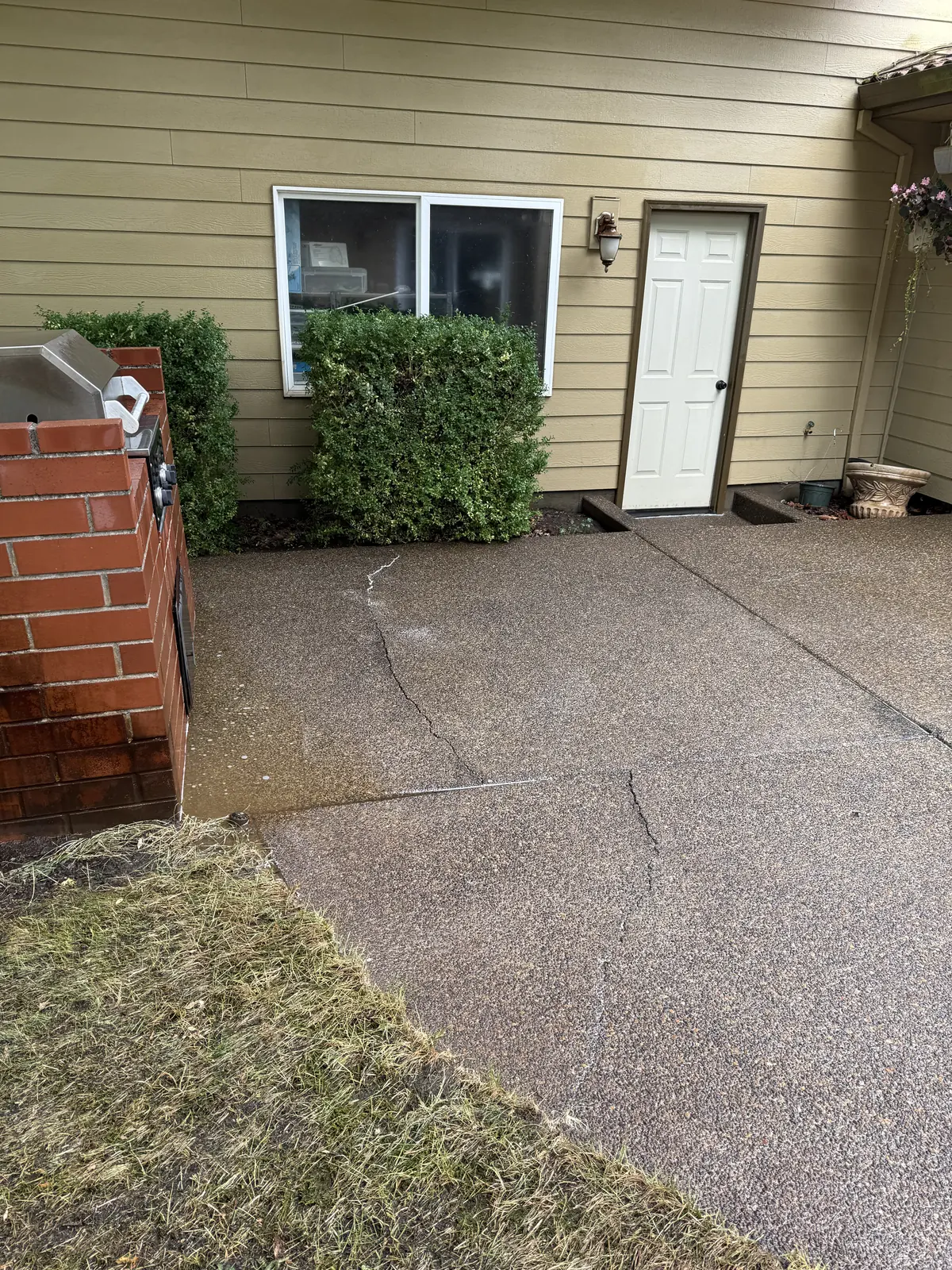 Clean concrete patio beside brick grill after pressure washing in Hillsboro Oregon