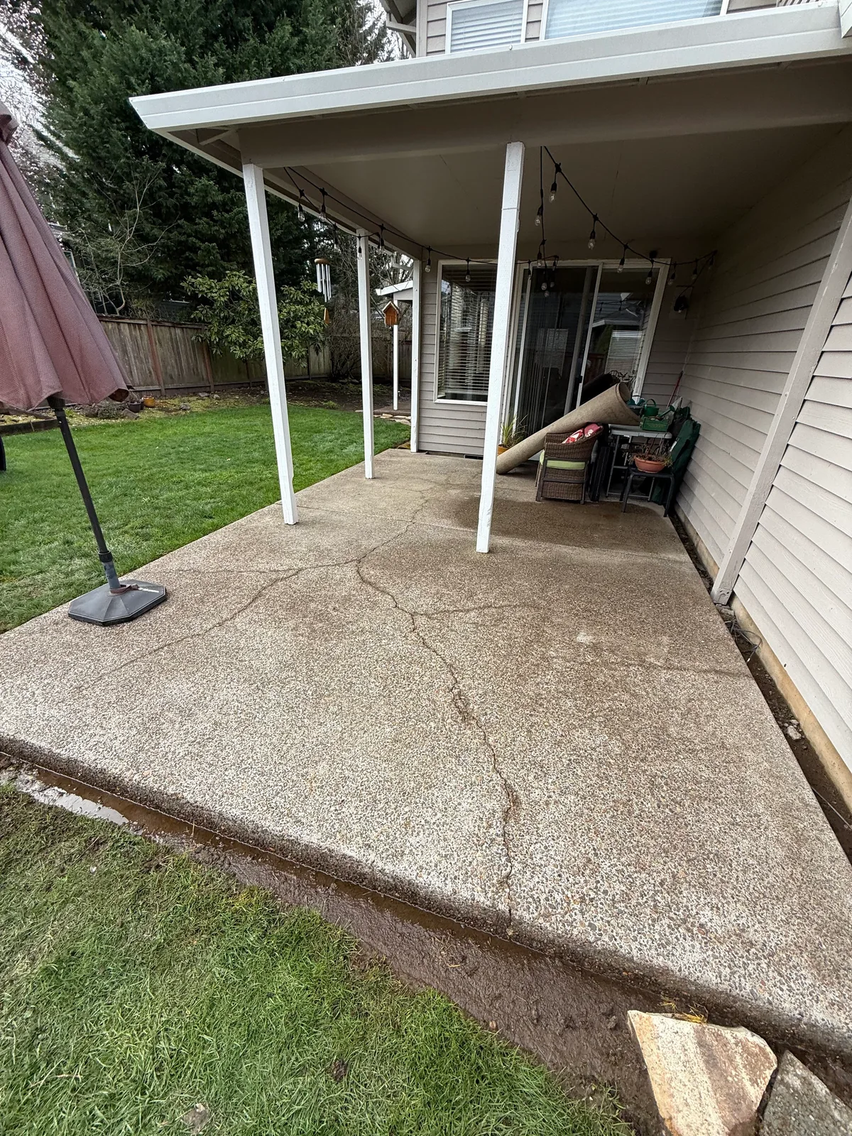 Covered patio after pressure washing with cleaner concrete and visible cracks in Hillsboro