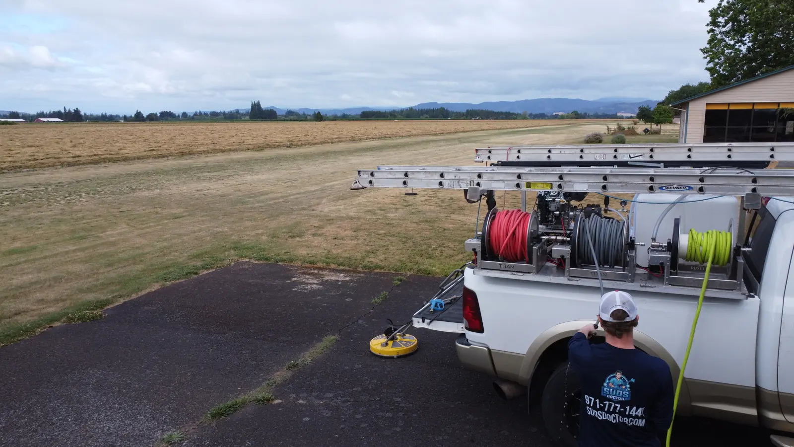 Suds Doctor pressure washing truck and technician beside a Hillsboro airstrip