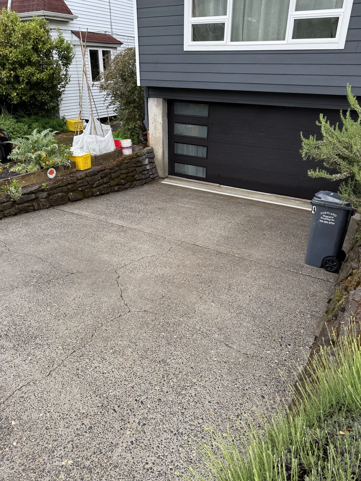 Cleaned Portland driveway after pressure washing near a garage and stone retaining wall