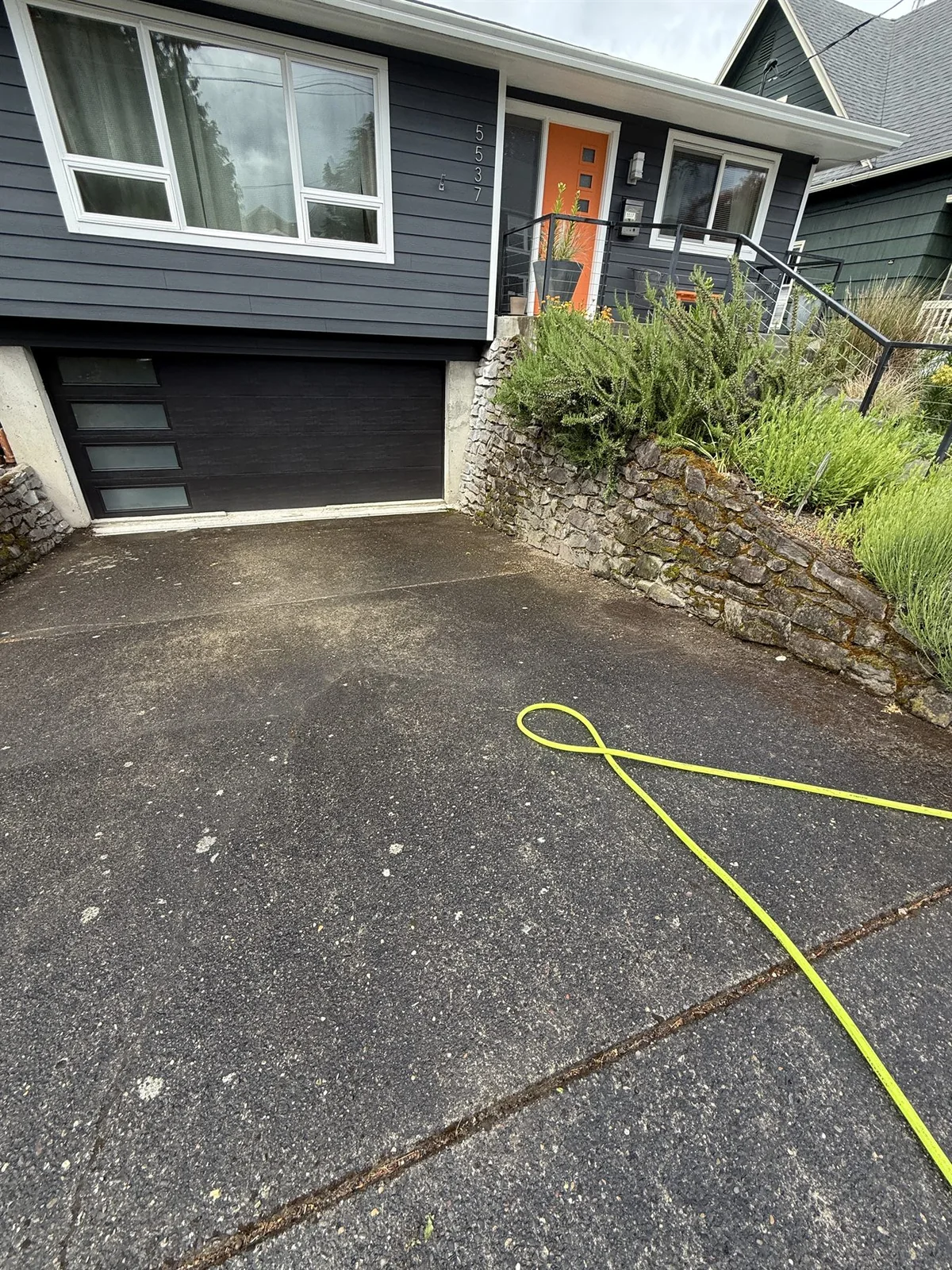Dirty Portland driveway before pressure washing with dark buildup near the garage
