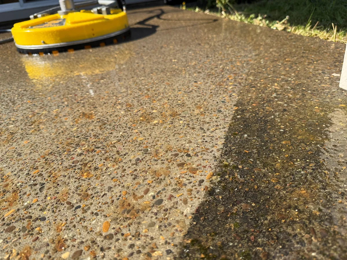 Pressure washing concrete with a clean line through moss and algae in Beaverton Oregon