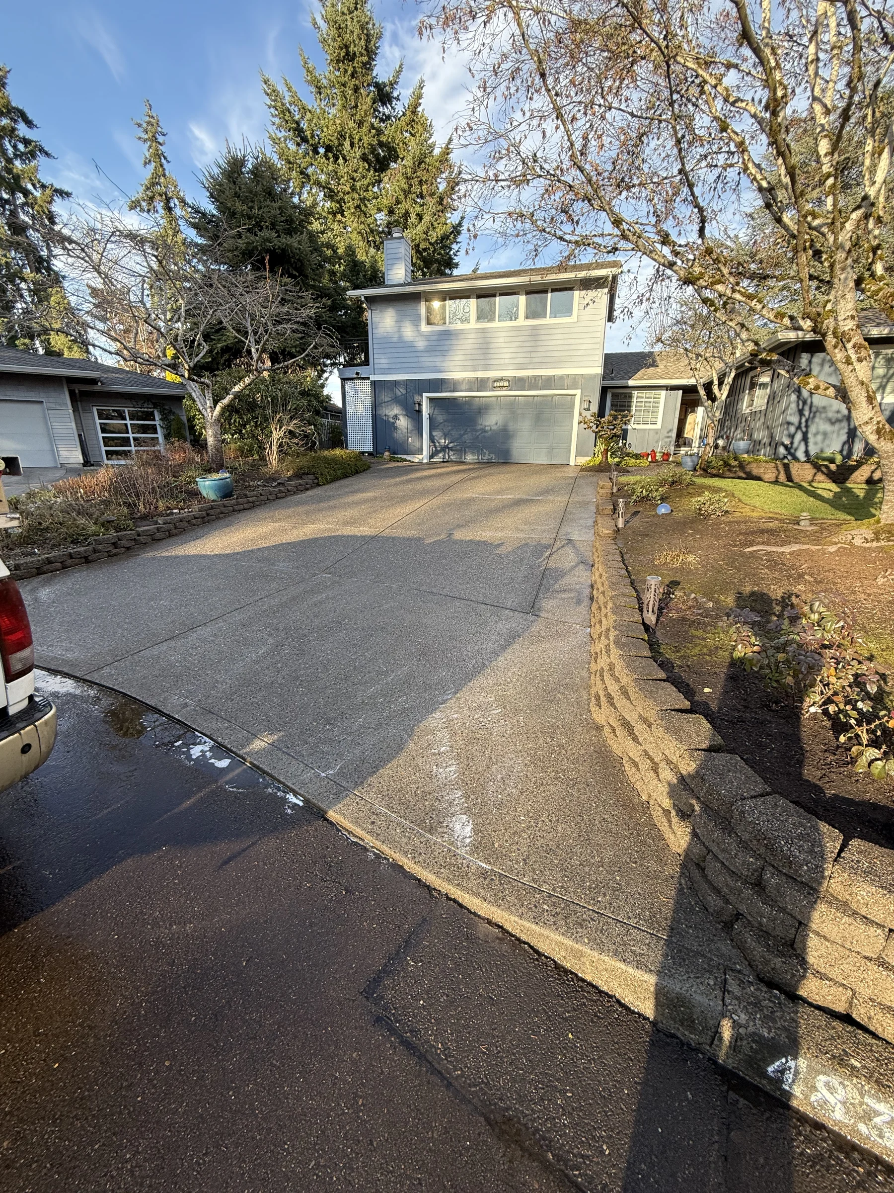 Clean driveway after pressure washing at a Rock Creek home with a small retaining wall beside the drive