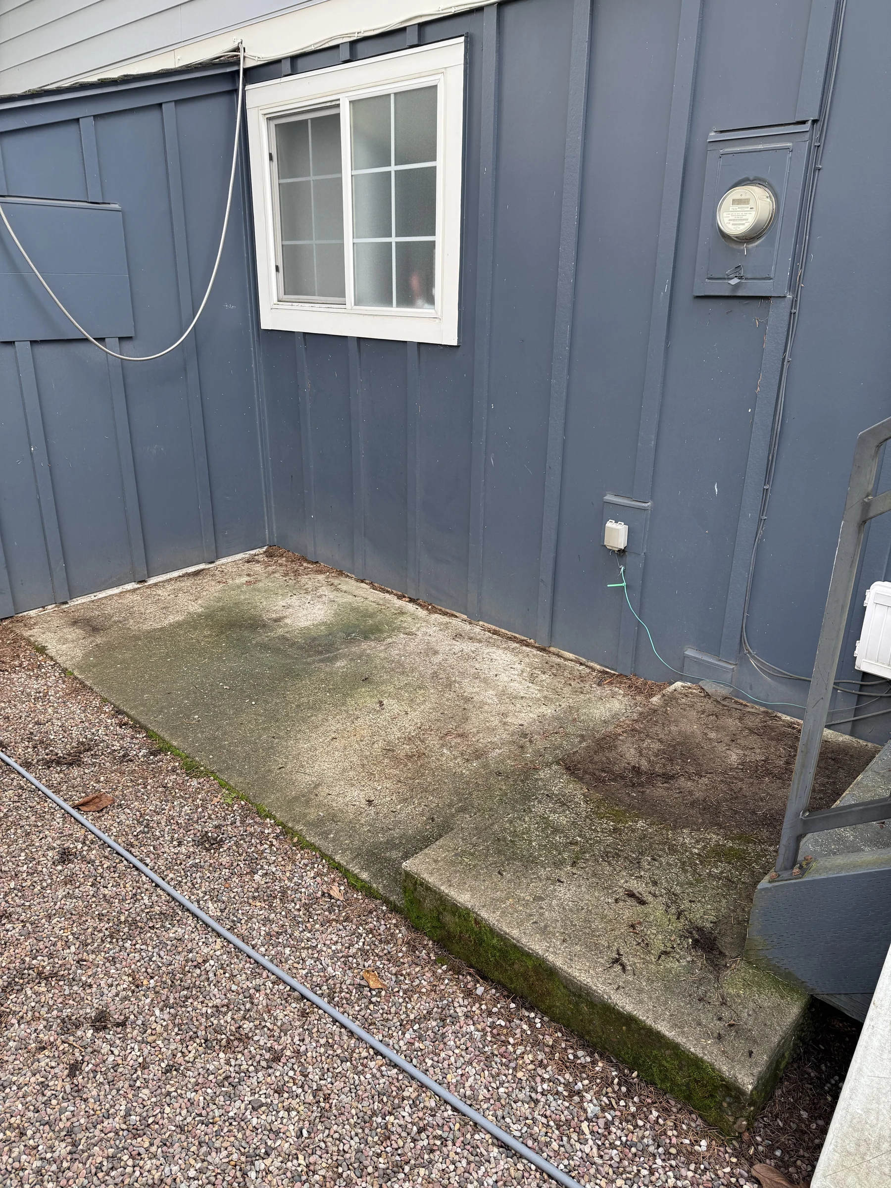 Small house-side patio pad before cleaning at a Rock Creek home