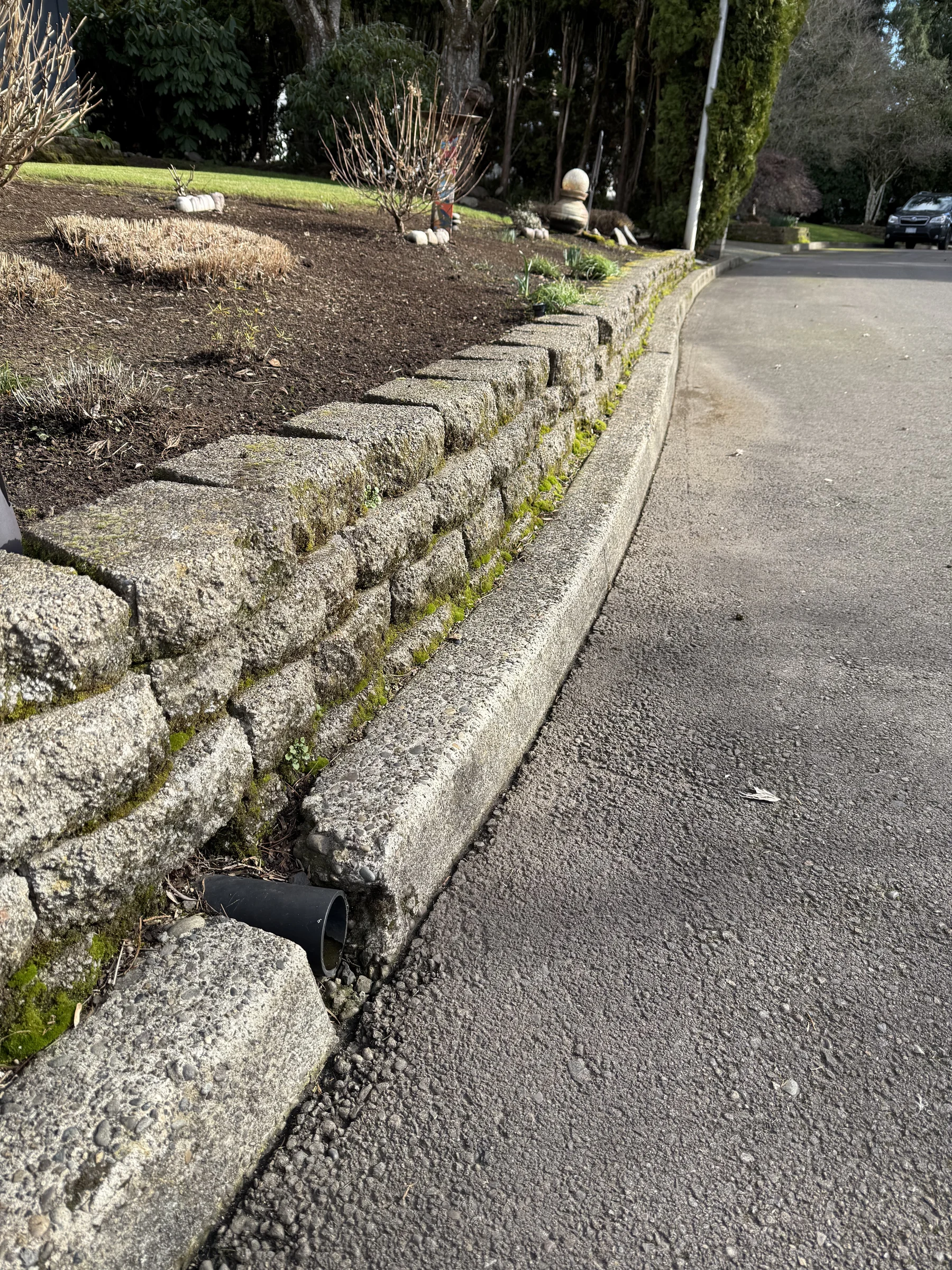 Close view of a block retaining wall beside a driveway during Rock Creek pressure washing