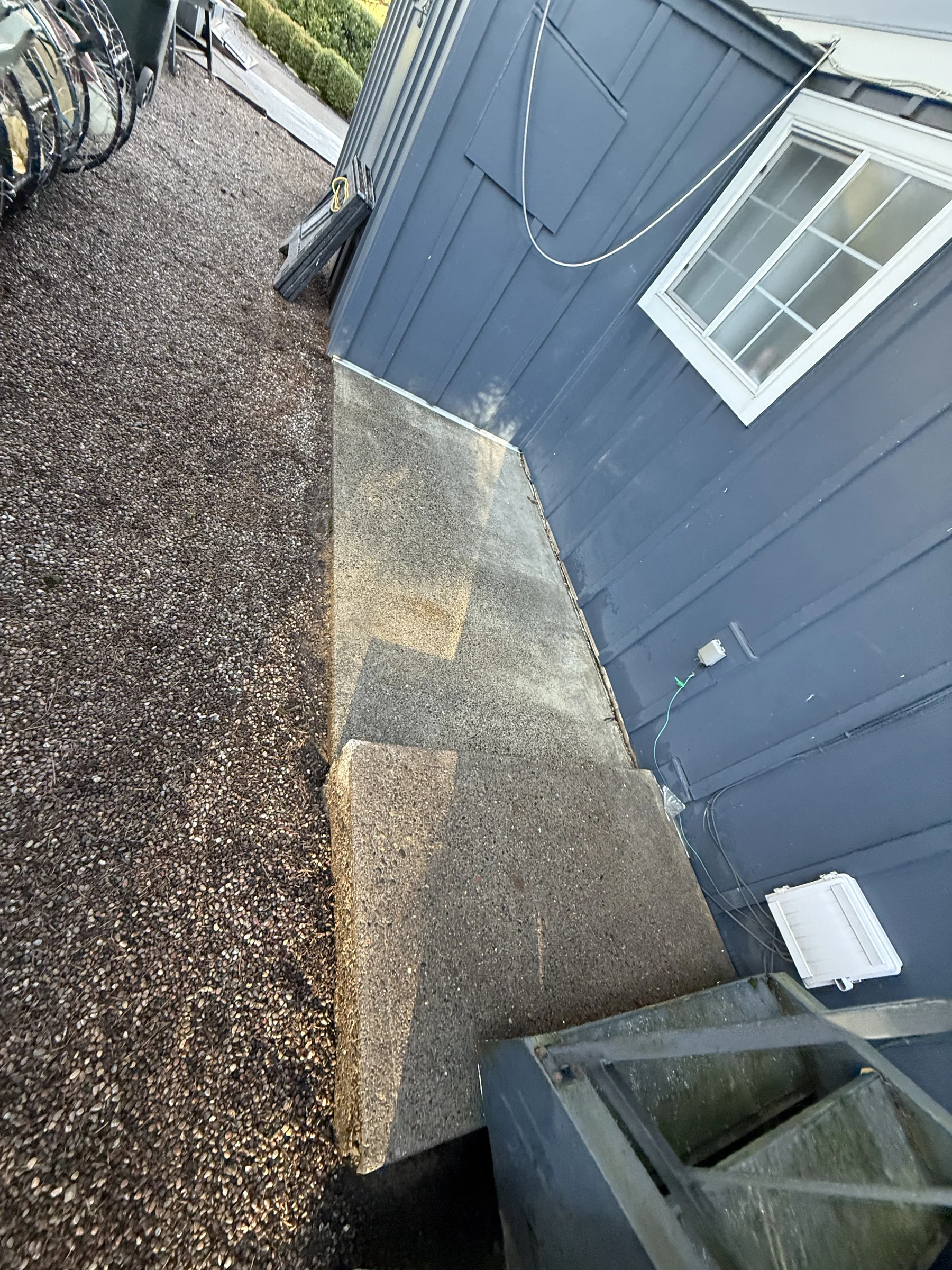 Side patio concrete pad near siding during a Rock Creek pressure washing project