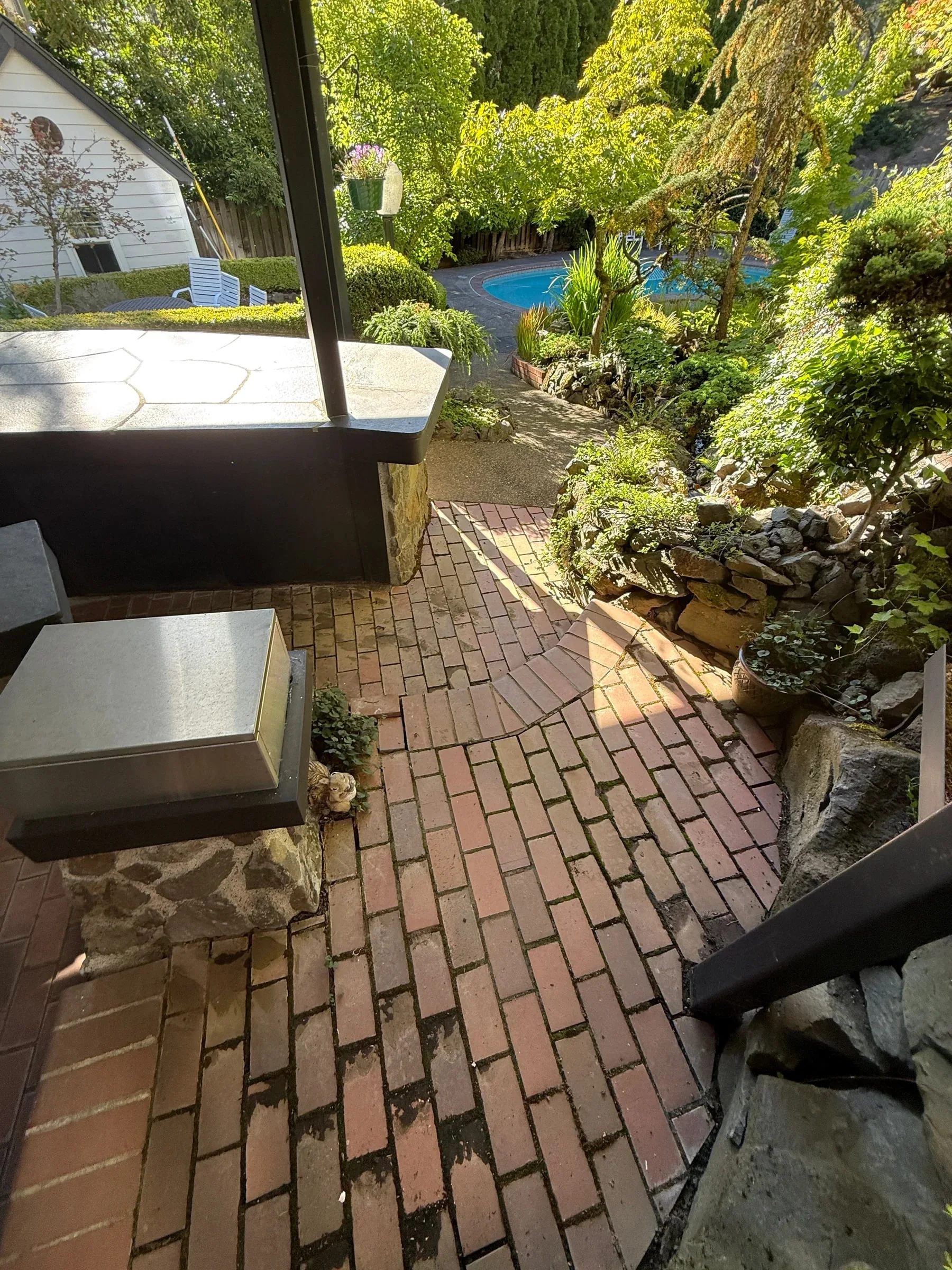 Brick outdoor kitchen floor with dark organic buildup in the joints before cleaning