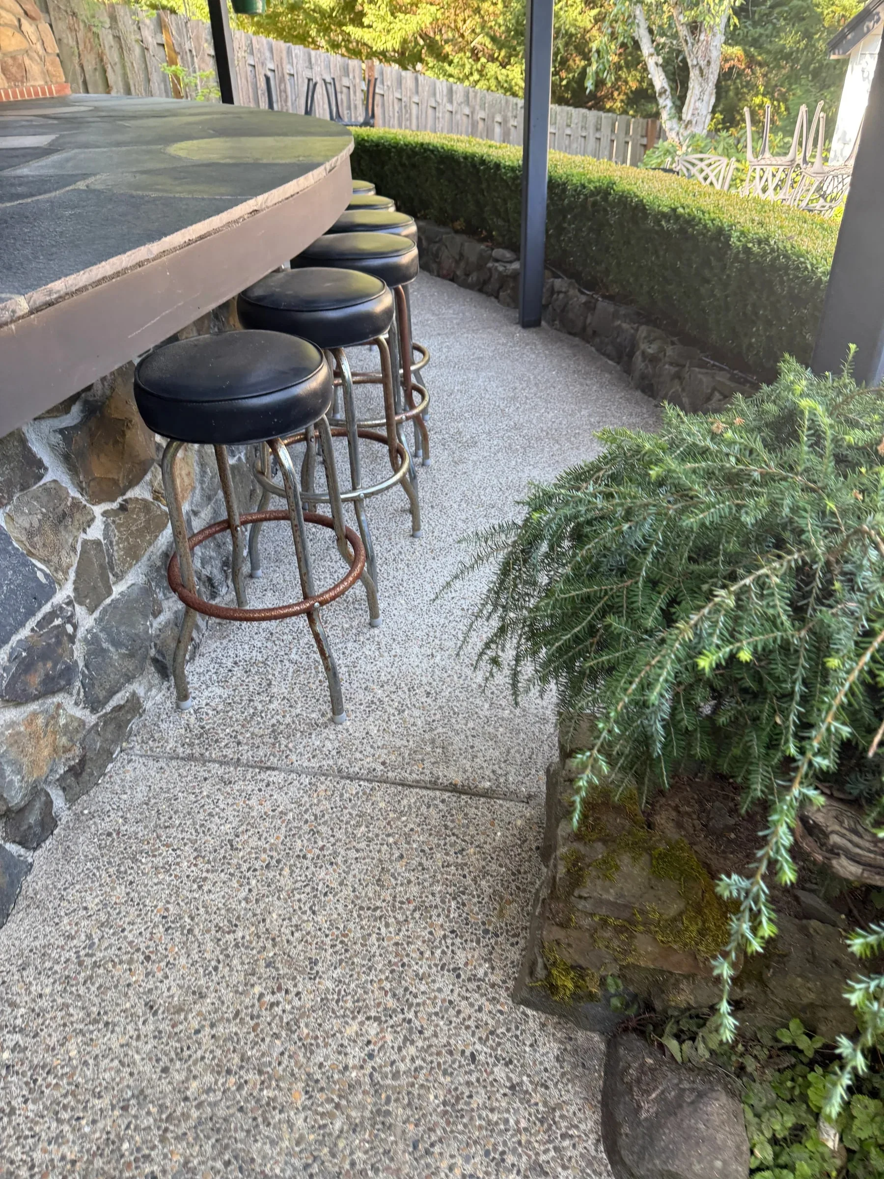 Cleaned exposed-aggregate walkway and seating area beside an outdoor kitchen