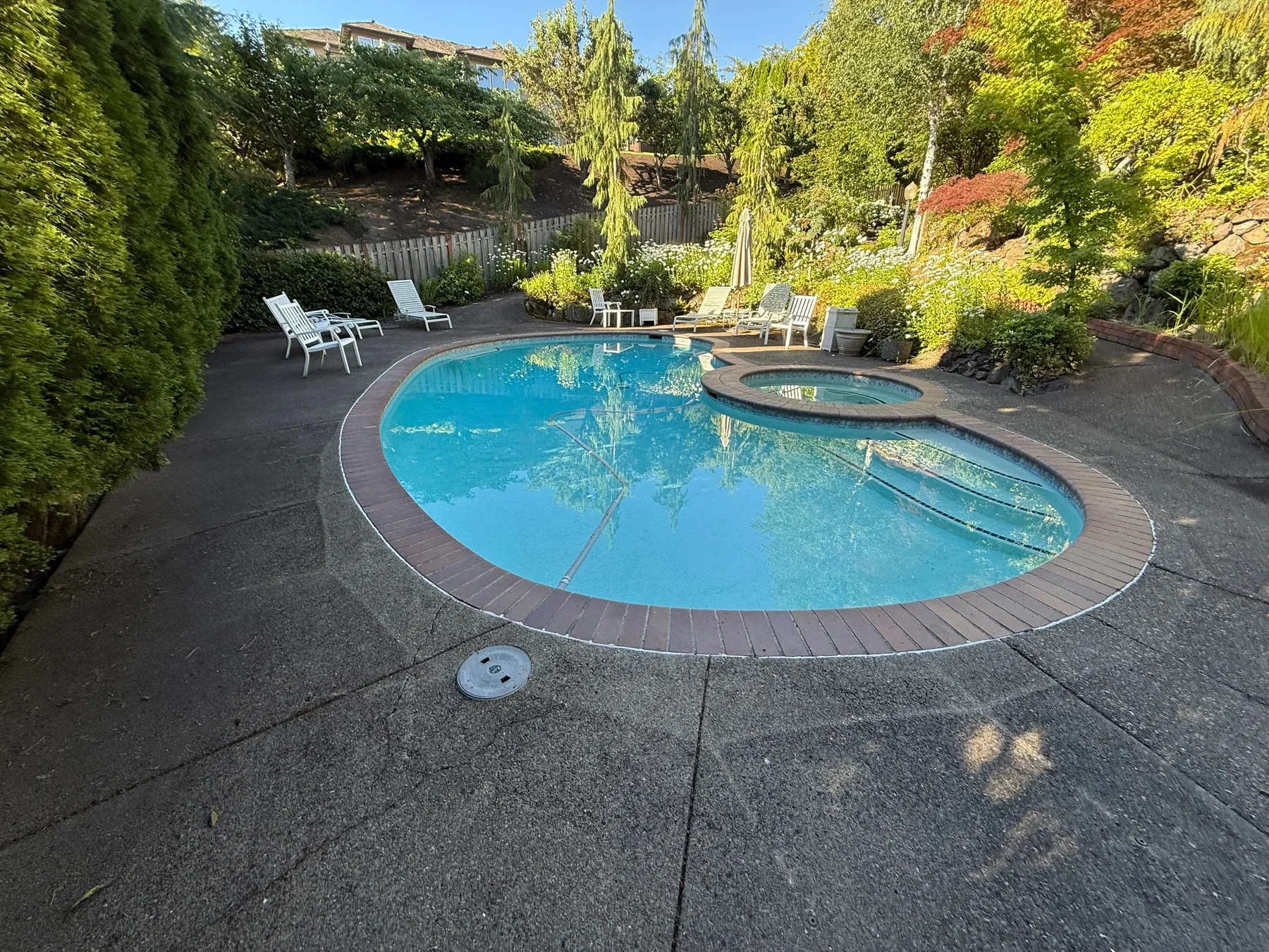 Exposed-aggregate pool deck with dark organic buildup before cleaning in West Beaverton